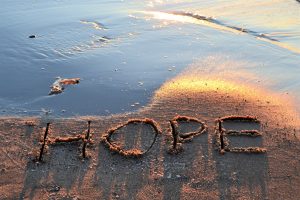 The word hope written in the sand on the beach at sunset